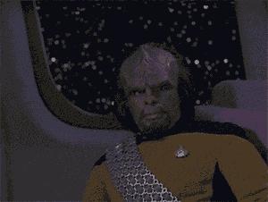 Bald alien with goatee and yellow uniform, wearing headphones