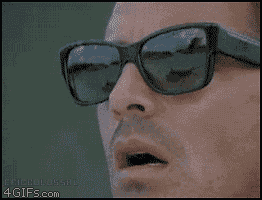 Guy with sunglasses on, looking surprised. Reflection in glasses shows an airplane