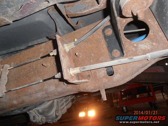 Underside view of rusty vehicle frame with brake lines and differential