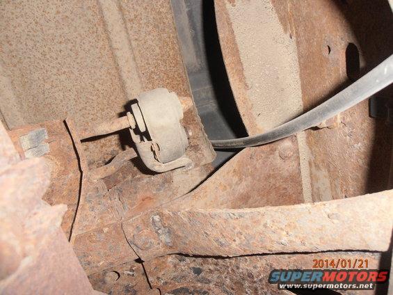 Close-up of rusted vehicle frame showing a suspension bushing and bracket