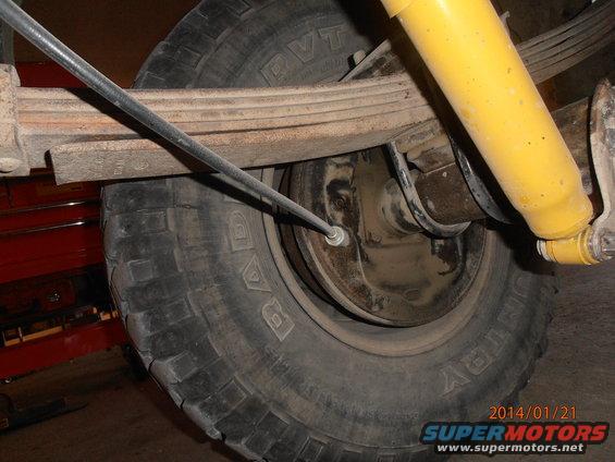 Close-up of a vehicle's rear tire and suspension components, including a yellow shock absorber and leaf springs