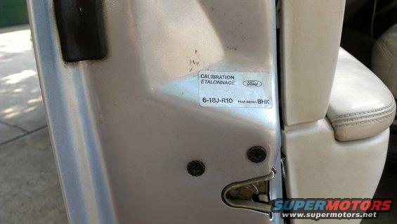 Door jamb sticker with Ford logo and calibration information, next to a beige leather seat