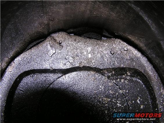 Damaged piston with metal fragments and scoring inside a cylinder bore