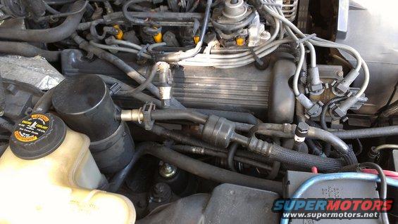 Engine bay with coolant reservoir, air intake, spark plug wires, and engine cover visible