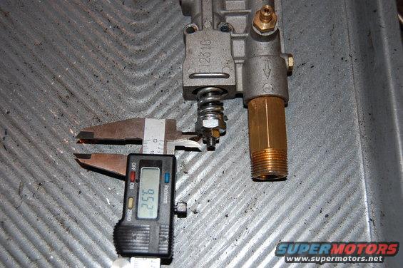 Digital caliper measuring a brass fitting on a pressure washer pump part. The caliper reads 9.52