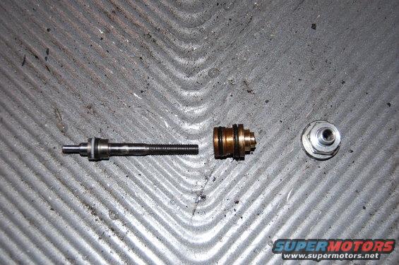 Valve stem, brass valve body, and nut on textured surface