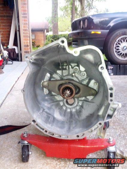 Transmission bell housing on red dolly, with a 1989 BMW 3 Series in the background