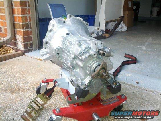 Aluminum transmission on a red and white engine stand with straps