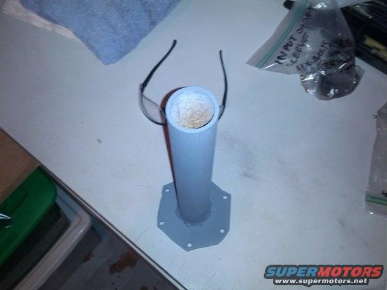 Gray pipe with a hexagonal base, resting on a table with a pair of glasses on top. Bag of bolts visible