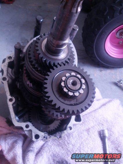 Transmission gears with a pink-rimmed wheel in the background