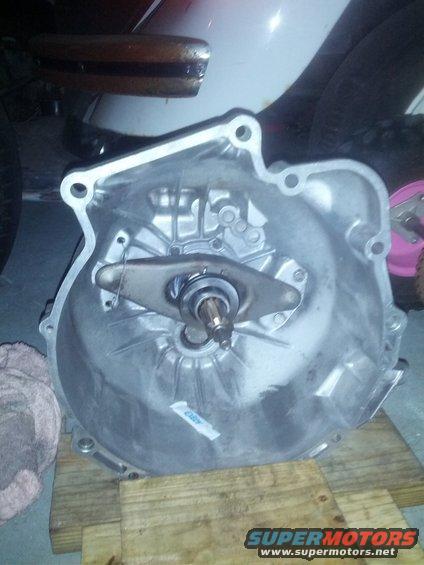 Transmission bell housing with clutch fork and bearing, resting on wooden blocks