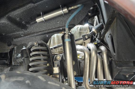 Undercarriage of a vehicle showing suspension springs, shocks, and exhaust headers