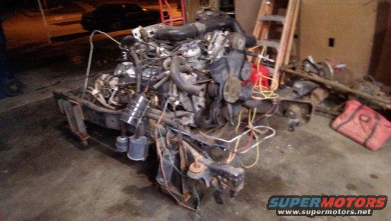 Engine assembly with hoses and wires, resting on a stand
