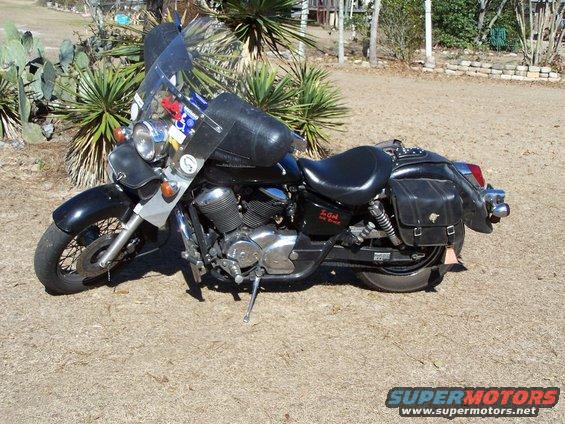 Black motorcycle parked outside, has a large windshield and leather saddlebags