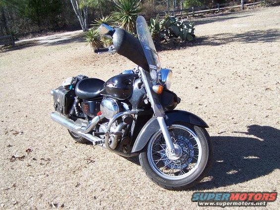 Black motorcycle with a windshield and saddlebags parked on a gravelly surface