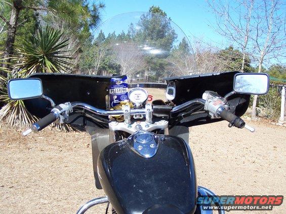 Motorcycle handlebars, mirrors, and fuel tank with a clear windshield