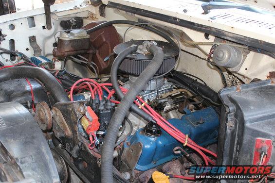 Engine bay with carburetor, distributor, and red spark plug wires
