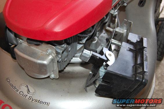 Close-up of a Honda lawn mower engine with red cover and silver casing. Part of the black plastic housing is detached