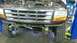1996 Ford Bronco - This Ford truck is on a lift with its front end exposed, revealing the grille and engine components.