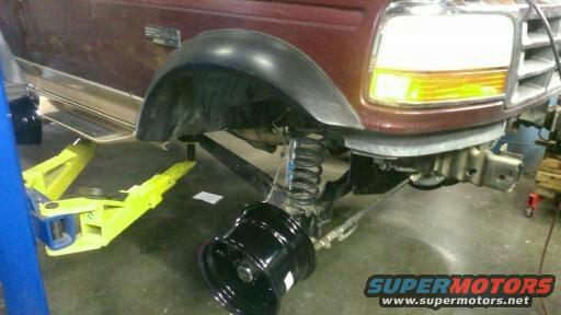 Maroon Ford Bronco front fender and suspension on a lift, with a detached wheel