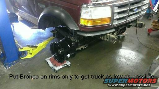 1996 Ford Bronco front end on a lift, front wheel removed and placed on a dolly