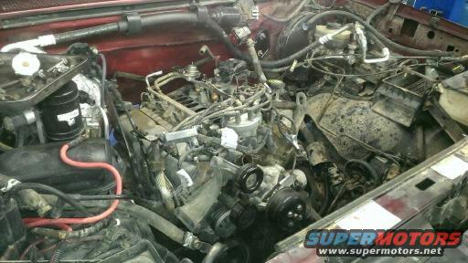Engine bay with many hoses and wires, some parts removed