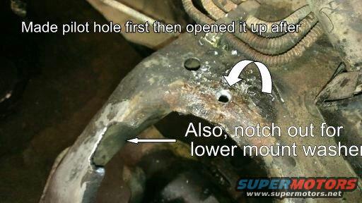 Close-up of vehicle frame with arrows and text indicating modifications for a lower mount washer and pilot hole