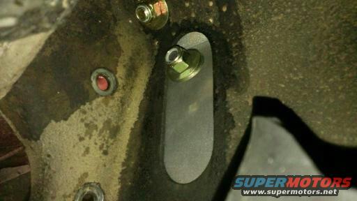 Close-up of vehicle frame showing bolts and a red indicator