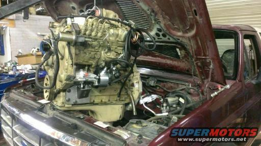 engine being lowered into a maroon truck with hood open
