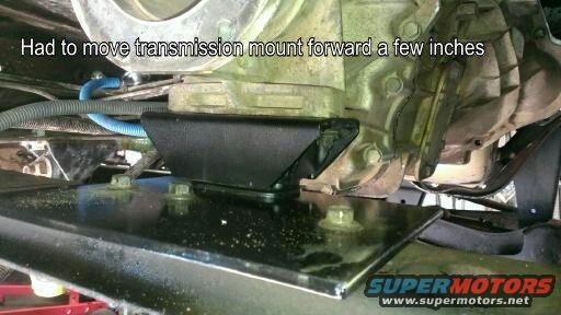 Underside of a vehicle showing a modified transmission mount with bolts and metal plates