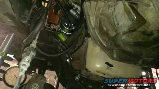 Underside view of a vehicle's mechanical components, including hoses and parts of the engine or transmission
