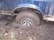 1987 Ford Bronco - A vehicle is stuck in thick mud, with its rear tire deeply embedded.