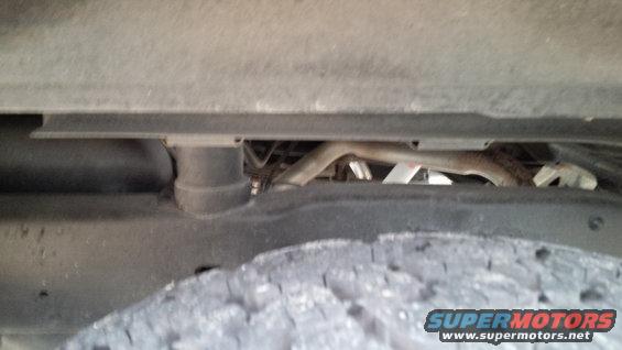 Underside view of a vehicle, showing the tire, frame, and exhaust pipe
