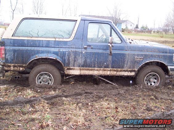 Blue 1987 Ford Bronco stuck in mud, side view