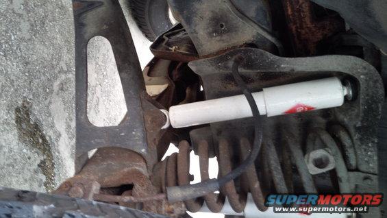 Close-up of vehicle suspension with a white shock absorber and coiled spring