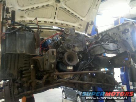 vehicle on lift with hood up, engine exposed, front suspension visible