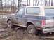 1987 Ford Bronco - This 1987 Ford Bronco is deeply stuck in thick mud, with trees and water in the background.