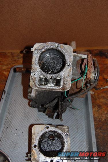 Engine cylinder head with carbon buildup and two valves visible, next to another engine part