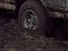 1987 Ford Bronco - This vehicle is deeply stuck in thick mud, with only the wheel and lower body visible.