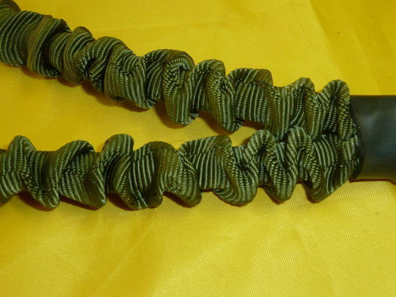 Close-up of two green elastic cords with ruffled texture against a yellow background