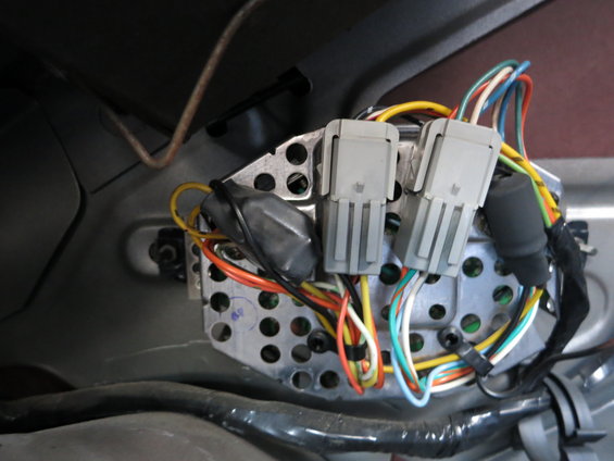 Close-up of gray electrical connectors and colorful wires attached to a metal bracket