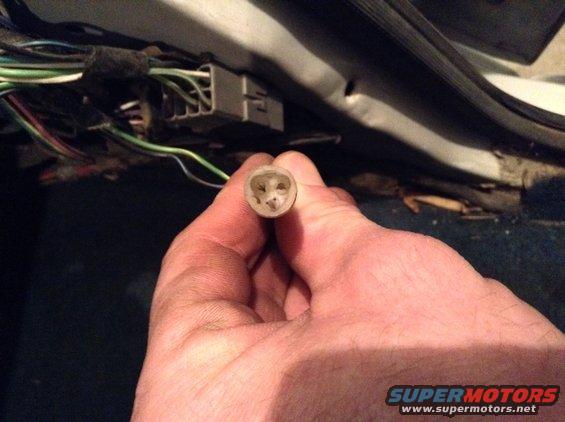 Hand holding a wiring harness connector with multiple wires visible in the background