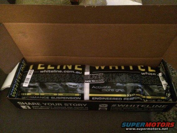Whiteline performance suspension parts in an open cardboard box. Text includes 'whiteline.com.au' and 'Activate more grip.'