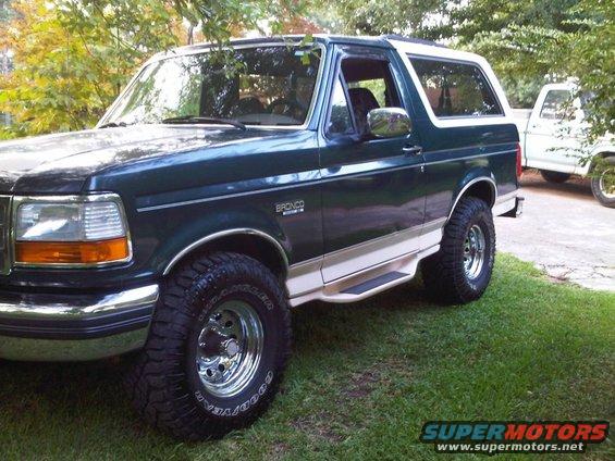 Dark green 1993 Ford Bronco with white top and tan stripe, side view