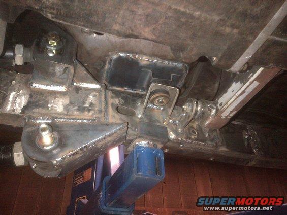Undercarriage of a vehicle with custom suspension modifications and a blue hydraulic jack
