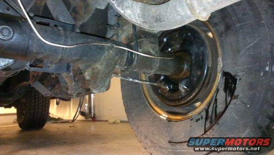 Underside view of a vehicle's rear axle, showing brake drum and fluid leak