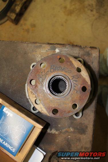 Rusty metal flange with splined center, marked '656 Bronco Rear'. Box of Koyo bearings nearby