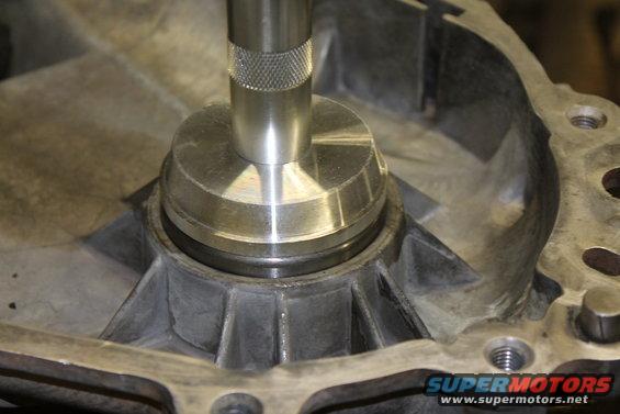 Close-up of a metal shaft being inserted into a cast metal housing, likely a transfer case component