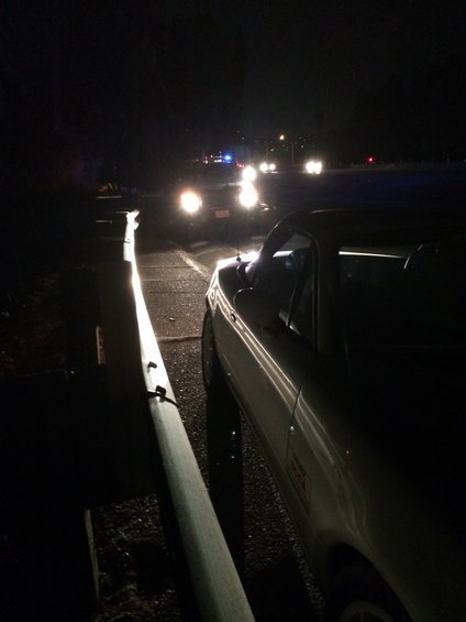 white convertible sports car parked on roadside at night, other cars with headlights on in background
