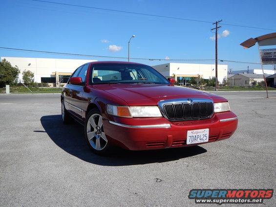 Red 2002 Mercury Grand Marquis parked outside a commercial building